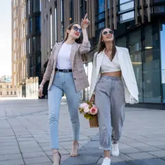 Dwie kobiety w modnych stylizacjach spacerują przed nowoczesnym budynkiem. Ich ubiór sugeruje, że to polskie marki znane na świecie.