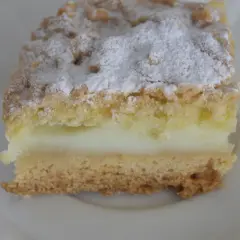 Kawałek ekspresowego kruchego ciasta z budyniem, posypana cukrem pudrem. Idealne na szybką przekąskę.