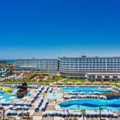 Widok na kompleks basenów i zjeżdżalni wodnych przy hotelu, z błękitnym morzem Eftalia Ocean w tle.