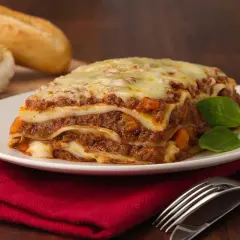 Herzhafte Lasagne mit Hackfleisch und Käse, dazu Baguette. Welcher Wein zu Lasagne passt, ist eine Frage des Geschmacks, aber ein kräftiger Rotwein ist oft ideal.