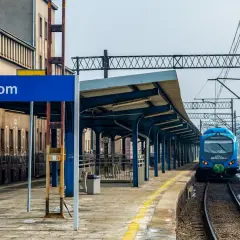 Niebieski pociąg na stacji Bytom, zadaszony peron i budynek dworca.