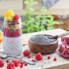 Un délice fruité : un pot de pudding de chia garni de fruits rouges, kiwi et orange, à côté d'une coupelle de graine de chia bienfait.