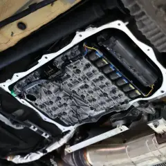 Widok od spodu na otwartą skrzynię biegów, gdzie widać skomplikowany mechanizm zaworów i cewek, kluczowy dla płynnego powershift.