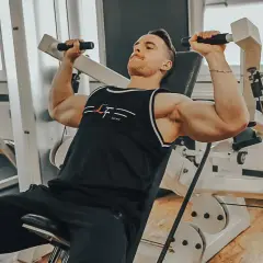 Mann trainiert Schultern an einer Maschine, ein intensiver superset workout für maximale Ergebnisse.