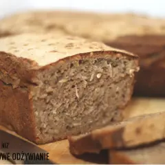 Krojony bochenek ciemnego chleba z ziarnami, obok leży nóż.