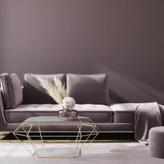 Ein luxuriöses Sofa in Mauve-Farbe mit einem geometrischen Couchtisch und einem runden Hocker.