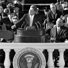 John F. Kennedy's inspiring **leadership style** is evident as he addresses a crowd, embodying youthful vigor and a call to action.
