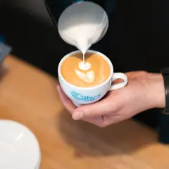 Barista tworzy latte art na podwójnym espresso z mlekiem.