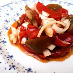 Deliciosa ensalada de pimientos asados con cebolla, bañada en un aderezo rojizo. Un plato lleno de sabor y color.