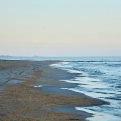 Plaża nad morzem Kaspijskim, które wysycha. W oddali widać zabudowania.