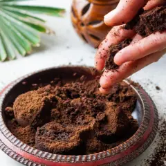 Mano esparciendo posos de café en un cuenco decorativo. El café molido se acumula en el cuenco, listo para ser reutilizado.