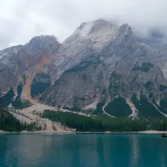 Boote auf einem türkisfarbenen See vor majestätischen Bergen, die an die Alta Via 1 erinnern.