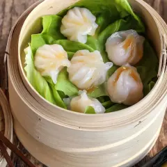 Délicieux ravioli crevette italien, cuits à la vapeur dans un panier en bambou, servis sur des feuilles de laitue.