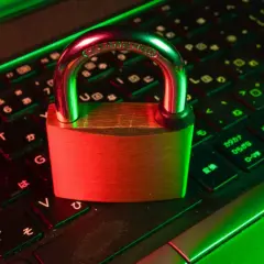 Un cadenas sur un clavier d'ordinateur, symbolisant la **sécurité informatique**. La lumière rouge et verte crée une ambiance de protection numérique.