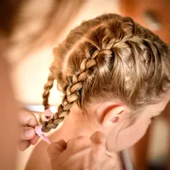 Urocze fryzury dla dziewczynek: warkocze z różową wstążką, tworzone z miłością.