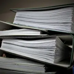 Stosy dokumentów w segregatorach. Czekając na wpis do księgi wieczystej, można się zastanawiać, ile trwa wpis do księgi wieczystej.