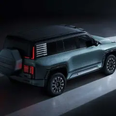 Nowoczesny, zielony BYD Yangwang U8 z kołem zapasowym z tyłu, w ciemnym otoczeniu.