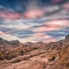Paisaje desértico con formaciones rocosas y un cielo dramático al atardecer, evocando la belleza del volcan Almería.