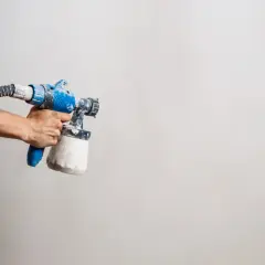Main tenant, prêt à peindre. Le pistolet à peinture, avec son réservoir rempli, attend la dilution parfaite pour un travail impeccable.