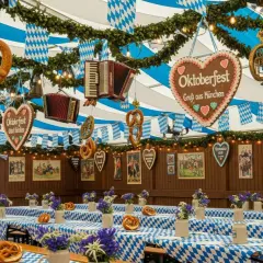 Wystrój namiotu Oktoberfest: obrusy w kratę, precle, akordeony, serca z piernika i dekoracje.