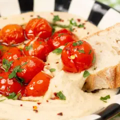 Cremiger veganer Tomatenaufstrich mit gerösteten Kirschtomaten, Kräutern und Brot.