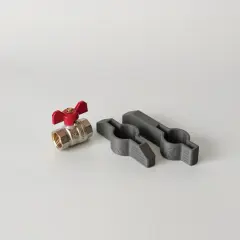Metalowy zawór z czerwoną rączką i dwa szare uchwyty, które pomogą, jak odkręcić zapieczony zawór wody.
