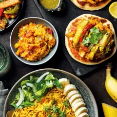 En härlig måltid med somalisk mat: ris, sallad, grönsaksröra och små bröd med fyllning. En banan och en citronklyfta fulländar bilden.