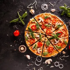 Pokrojona pizza z pomidorami, mozzarellą i bazylią na czarnym tle, otoczona składnikami.
