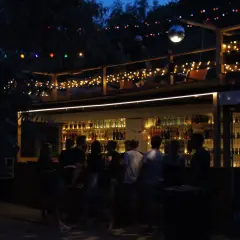 Nocna imprezowa ulica w Warszawie. Bar z kolorowymi światłami i ludźmi cieszącymi się wieczorem.