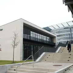 Moderne Architektur der FernUni in Hagen, NRW. Eine Person steigt eine breite Treppe hinauf.