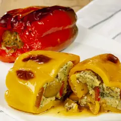 Peperoni ripieni senza carne, un piatto colorato e saporito. Un peperone rosso intero e uno giallo tagliato a metà, entrambi farciti con un ripieno gustoso.