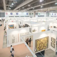 A bustling scene at the Mexico City Art Fair, with visitors exploring numerous white-walled booths showcasing diverse artworks.