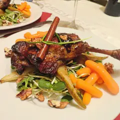 Pyszna kaczka francuska w sosie, podana z marchewkami, orzechami i kiełkami.