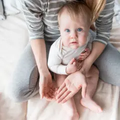 Niebieskooki maluch siedzi na kolanach mamy. Zastanawiamy się, ile czasu po uderzeniu w głowę dziecko nie może spać, gdy jest tak czujne.