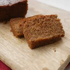 En skiva mjuk pepparkaka med pudersocker på en träskärbräda.