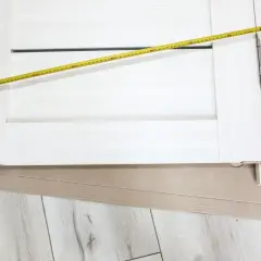 Białe drzwi z widoczną miarką. Mierzone skrzydło drzwiowe ma szerokość ok. 70 cm, co sugeruje jaki otwór na drzwi 70 będzie potrzebny.