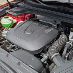 Motor de coche con cubierta negra, batería y depósito de refrigerante verde. ¿Cuántos caballos tiene un coche normal?