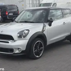 Srebrny mini paceman z czarnym dachem i felgami, zaparkowany na placu.