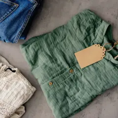 Ubrania na sprzedaż, jak na Vinted. Zastanawiasz się nad vinted podatek? Dżinsy, bluzka ecru i zielona koszula z metką.