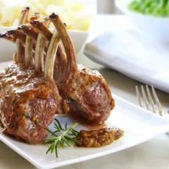 Un délicieux carré d'agneau rôti, nappé d'une sauce savoureuse, est servi avec une branche de romarin.