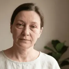 Frau mit leicht geschwollenem Augenlid, fragt sich: geschwollenes Augenlid wann zum Arzt? Sie blickt nachdenklich in die Kamera.