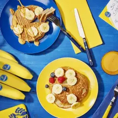 Pancakes con banana dopo allenamento, un pieno di energia. Frutta fresca e succo d'arancia per recuperare al meglio.
