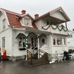 Vitt hus med rosa detaljer och juldekorationer. Skylt visar "Reception Restaurang". Kanske en titt på restaurang Solliden meny?