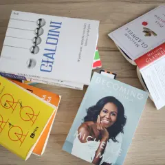 Kilka książek leżących na drewnianym blacie, w tym "Siła nawyku" i "Becoming".
