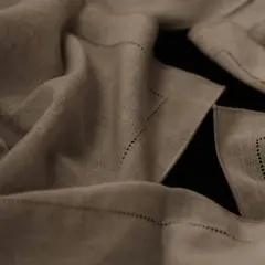 Draped linen fabric, perfect for breathable summer pants, features delicate dotted stitching along its edges.