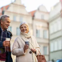 Uśmiechnięta para seniorów cieszy się kawą na spacerze. Idealne wycieczki dla emerytów i rencistów.