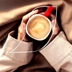 Dłonie trzymają filiżankę kawy Nescafé z bogatą cremą. Idealna kofeina na chłodny dzień.
