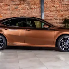 Brązowy sedan, jeden z najwygodniejszych samochodów, prezentuje się stylowo na tle ceglanej ściany.
