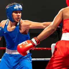 Two young boxers in a ring, one in blue, the other in red. This image shows the intensity of amateur boxing, where age limits are strictly enforced for safety.