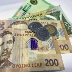 Banknoty i monety, które pokazują, jaka waluta w Albanii. Widoczne są nominały 20, 200 i 1000 leków.